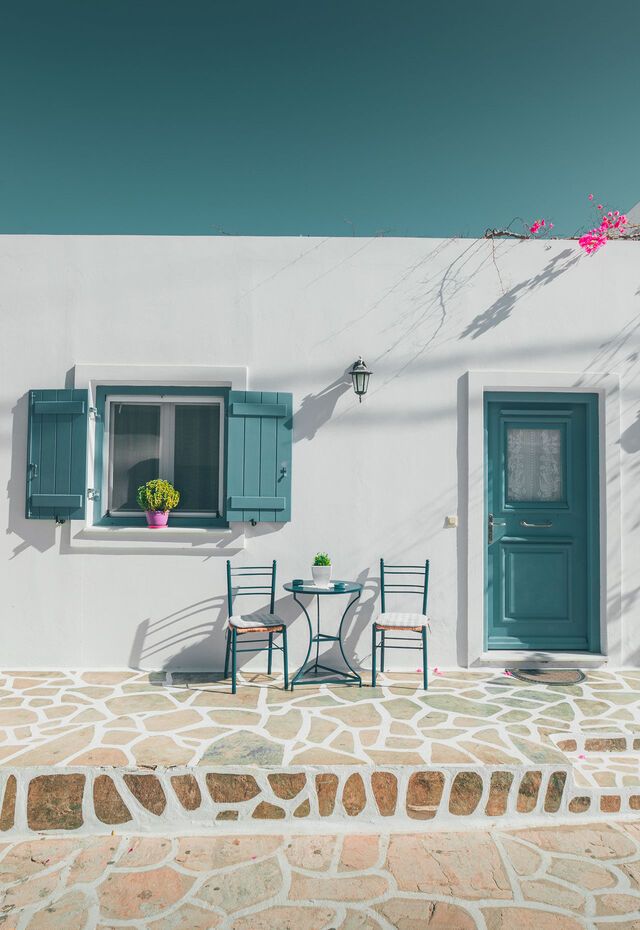 Traditional whitewashed Cycladic house in Antiparos with blue doors and colorful bougainvillea.