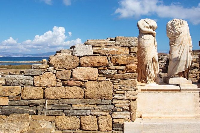 Ancient ruins on Delos Island, with well-preserved columns and the remnants of temples against a backdrop of blue skies.