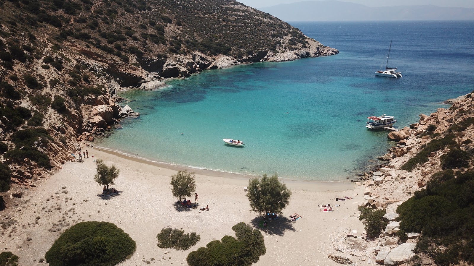 Aerial view of a pristine beach in Irakleia, surrounded by rugged cliffs and deep blue sea
