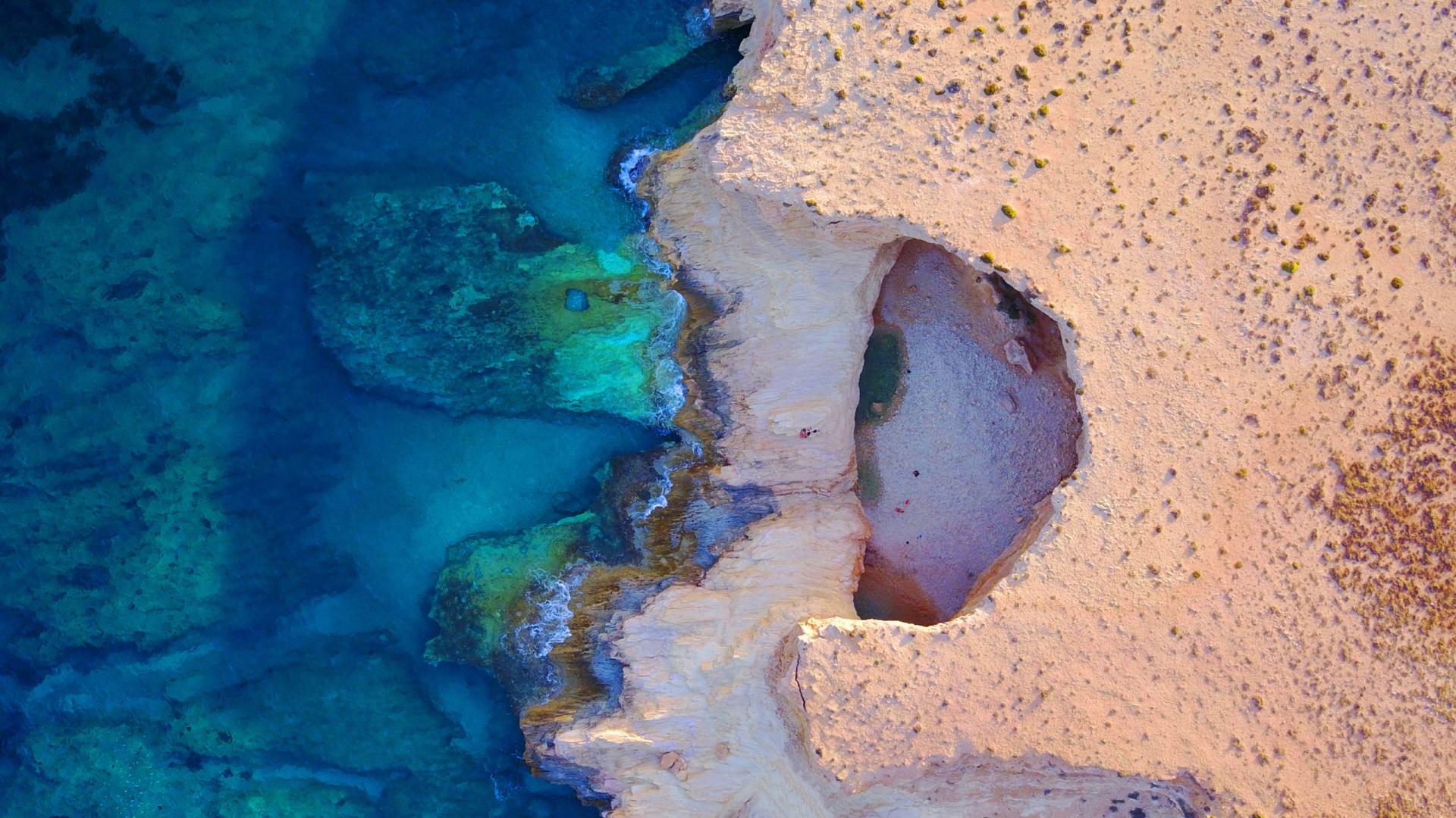 Crystal-clear waters flowing through the iconic Sevil Eye rock arch in Koufonisia.