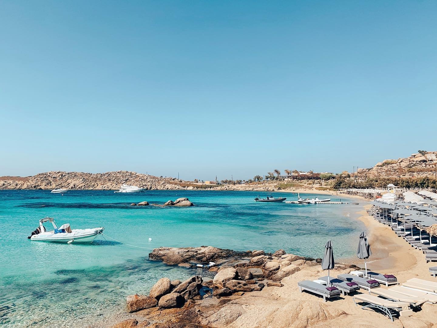 The lively south coast of Mykonos, where visitors enjoy beachside bars, crystal-clear waters, and golden sands."