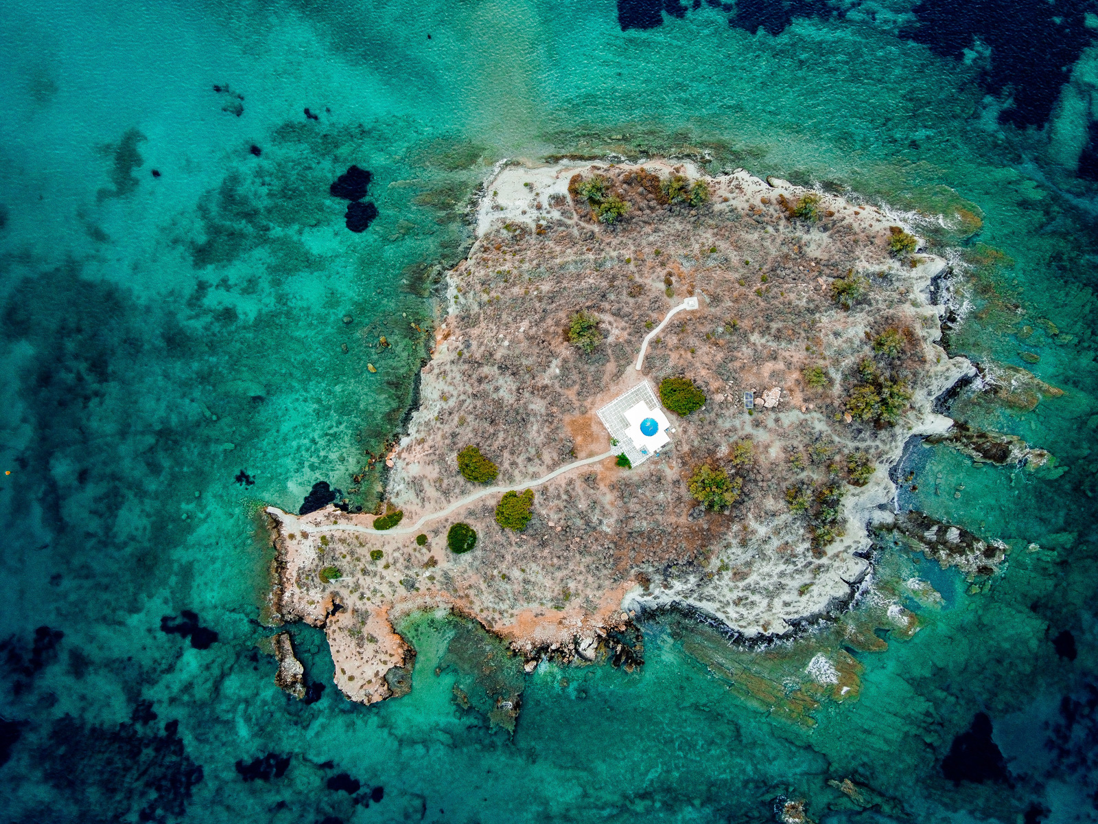 Secluded cove on Paros Island, surrounded by rugged cliffs and shimmering blue sea.