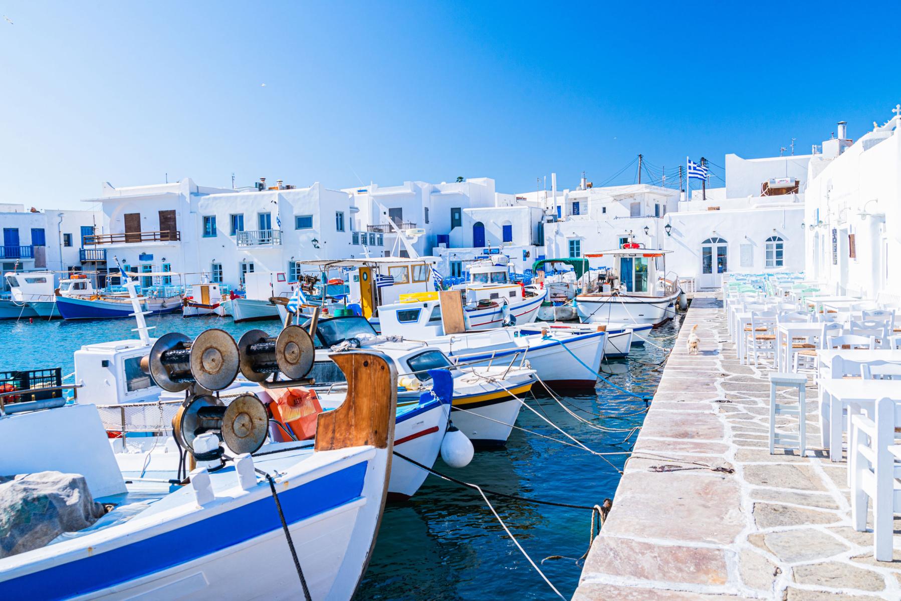 Bustling harbor of Paros with traditional Greek tavernas and whitewashed buildings in the background.