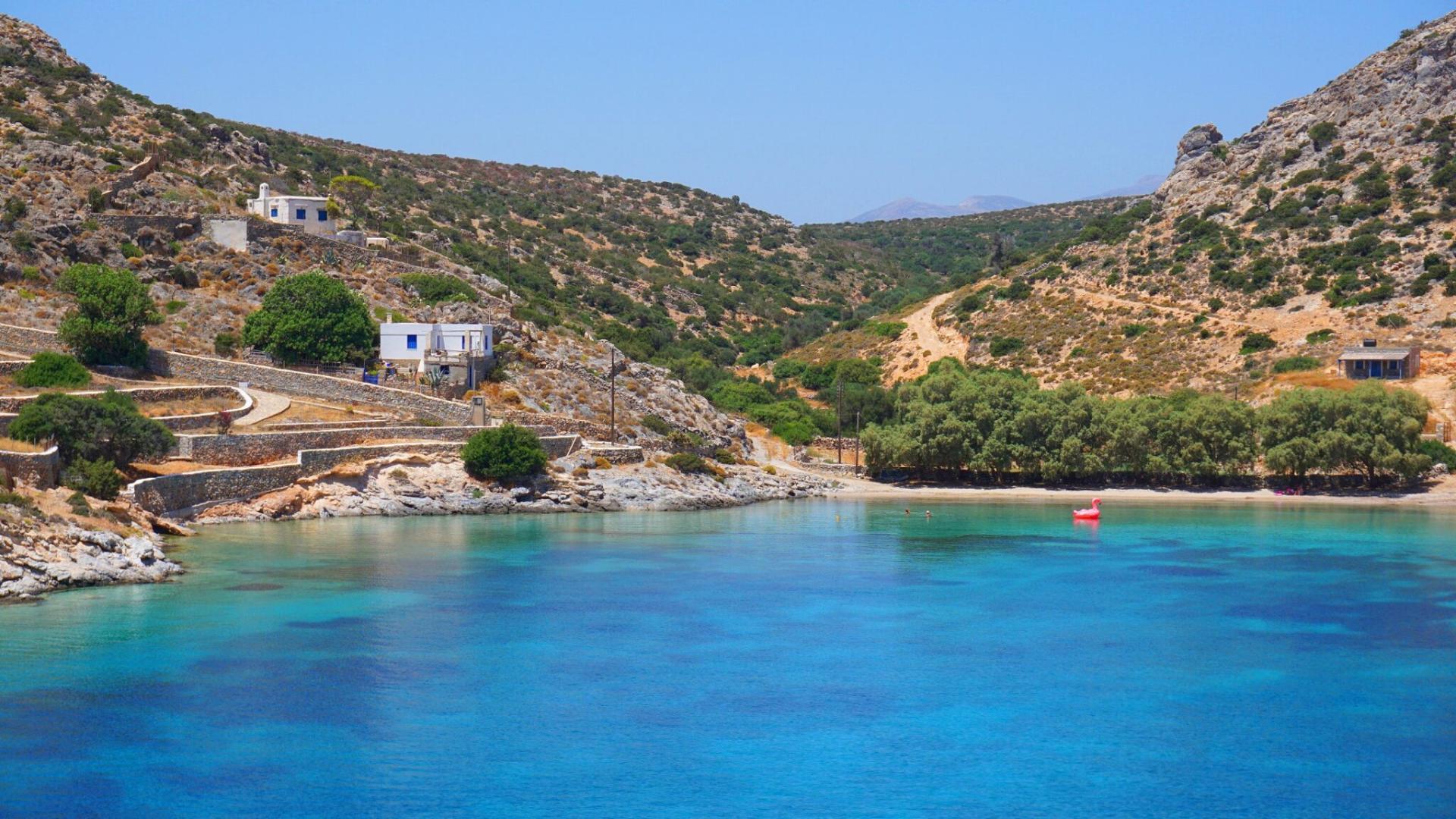"Yacht anchored near a stunning beach on Schinoussa, with transparent waters reflecting the sunlight
