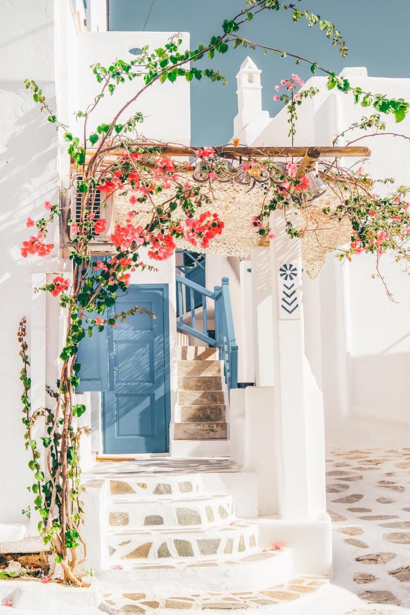 raditional Cycladic street in Sifnos with blue doors, blooming bougainvillea, and cozy cafés