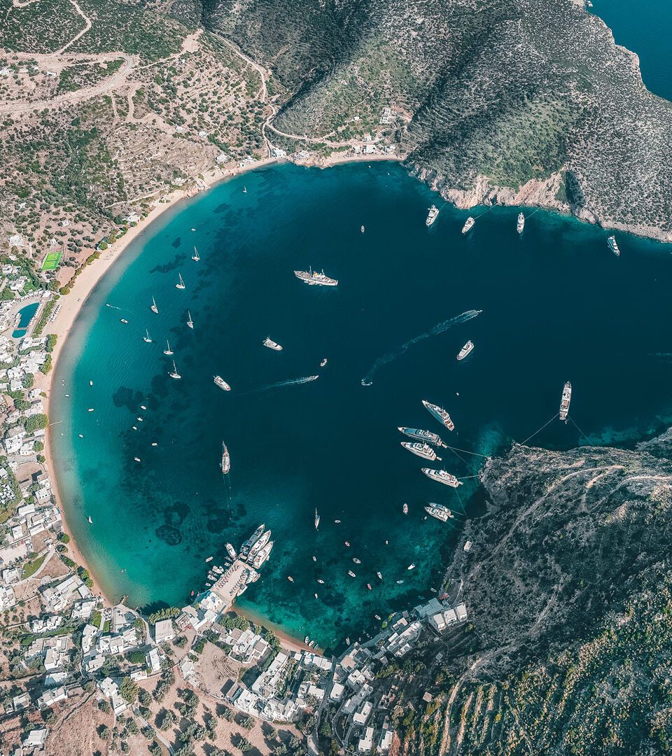 Aerial view of Sifnos Port, showcasing a picturesque seaside village and deep blue waters.