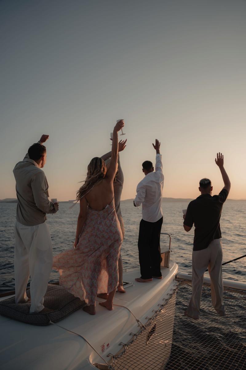 Guests celebrating and dancing to upbeat music, enjoying the party vibes on board a luxury yacht in Mykonos.