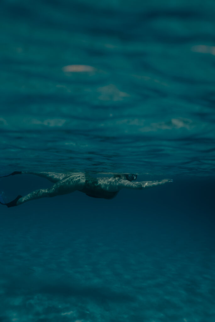 A snorkeler diving into the turquoise Aegean Sea, discovering the rich underwater world of Mykonos.