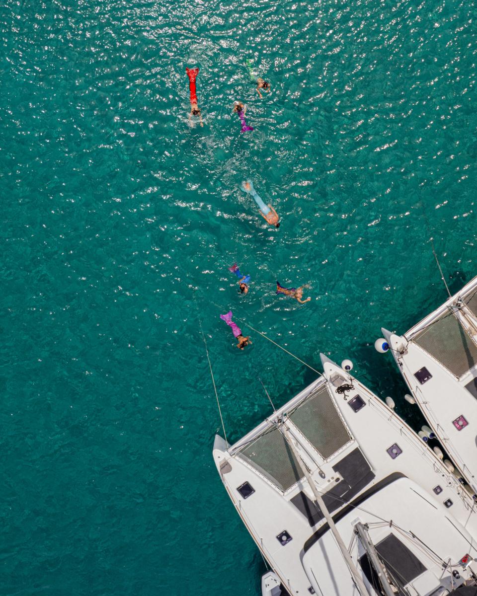 ests enjoying a private catamaran charter in Mykonos, with spacious deck seating and breathtaking views of the Aegean Sea.