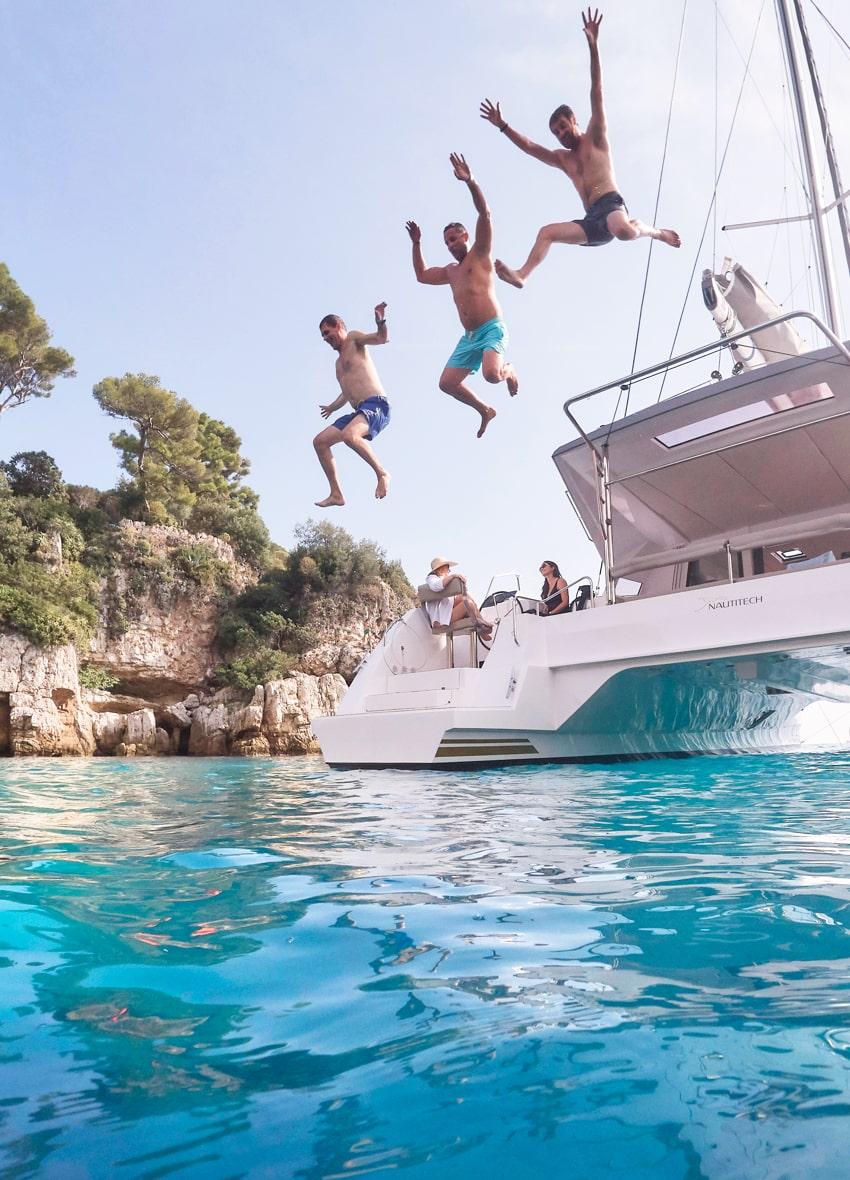 Guests diving into crystal-clear waters from a catamaran in Mykonos.