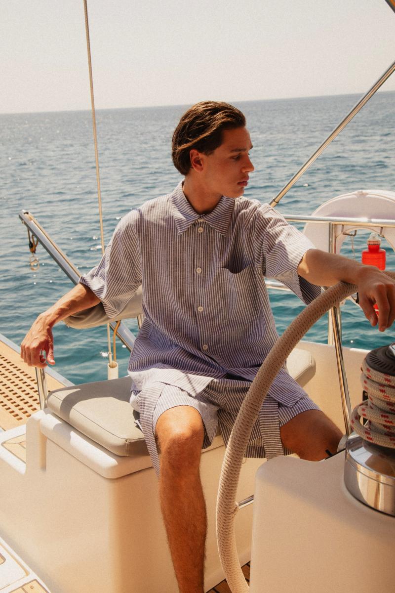 Man at the Helm Steering a Sailing Yacht – "A confident man steering a sailing yacht, hands gripping the wheel as the wind fills the sails