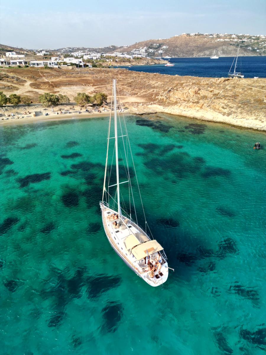Sailing Yacht Anchored Near Rhenia Island – "A luxury sailing yacht anchored near Rhenia Island, surrounded by untouched natural beauty and pristine blue sea.