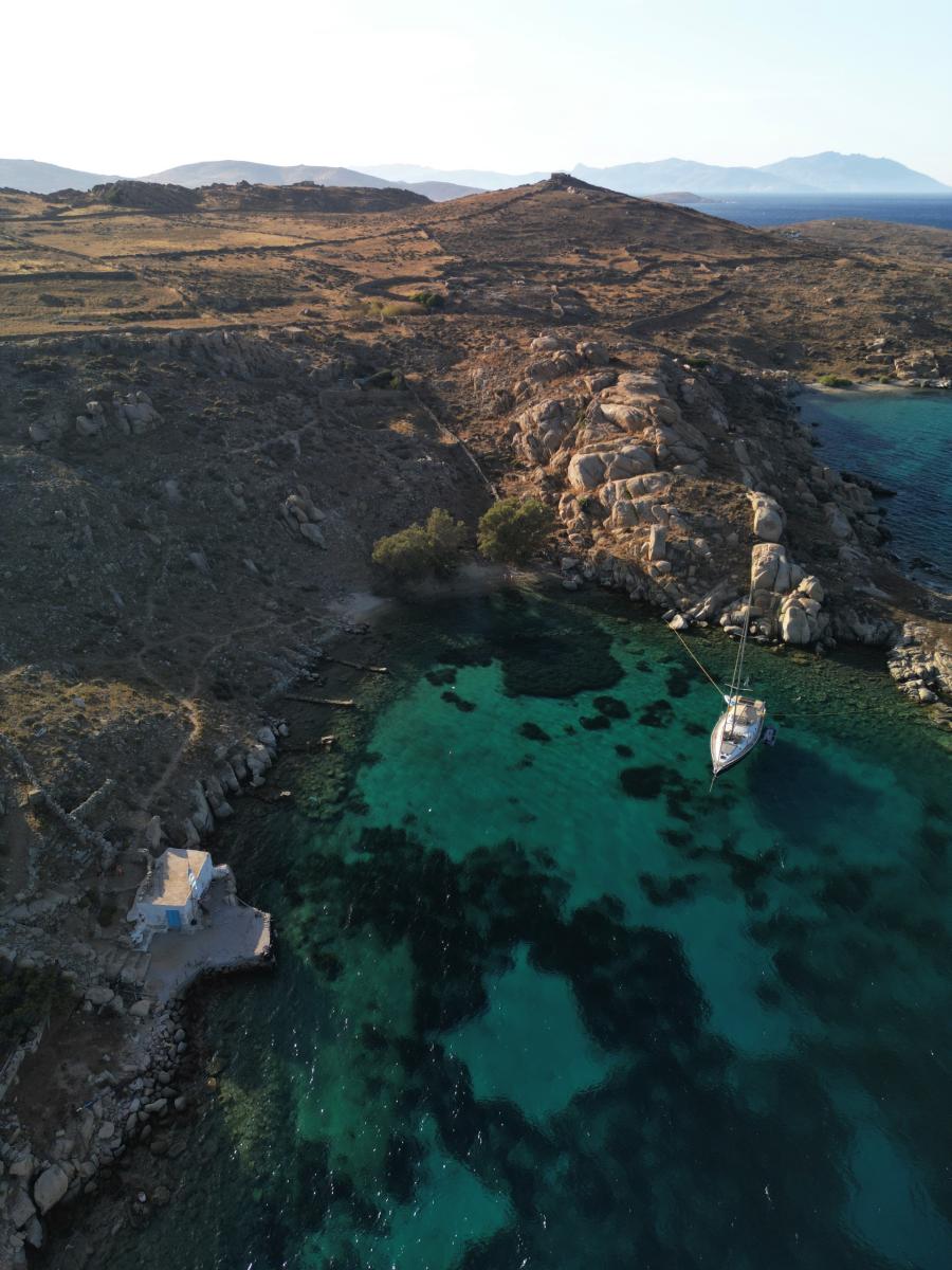 Sailing Yacht Anchored Near Rhenia Island – "A luxury sailing yacht anchored near Rhenia Island, surrounded by untouched natural beauty and pristine blue sea.