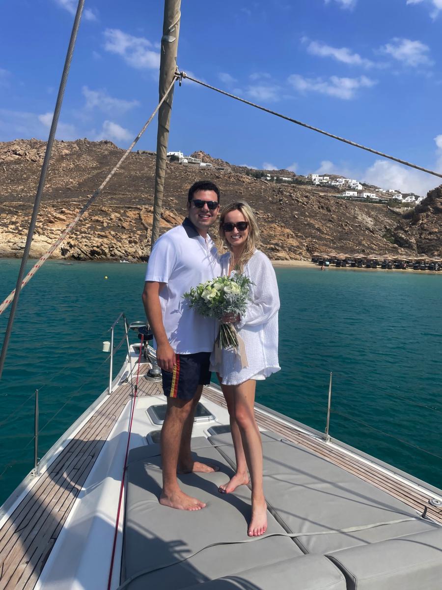 Tranquil Sailing Experience in Mykonos – "A couple holding hands on the bow of a yacht, taking in the peaceful beauty of the open sea